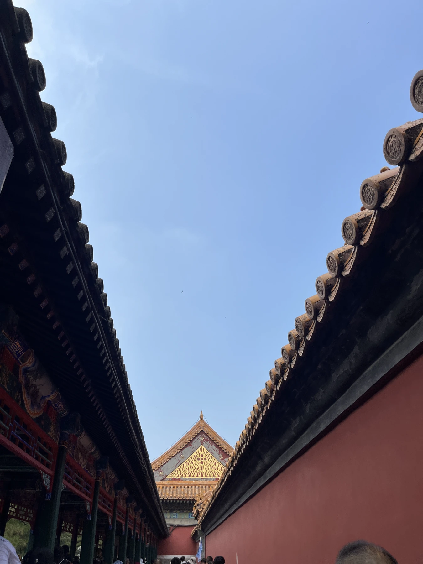 两侧寺庙屋檐与红墙向远处收拢，围住蓝色天空