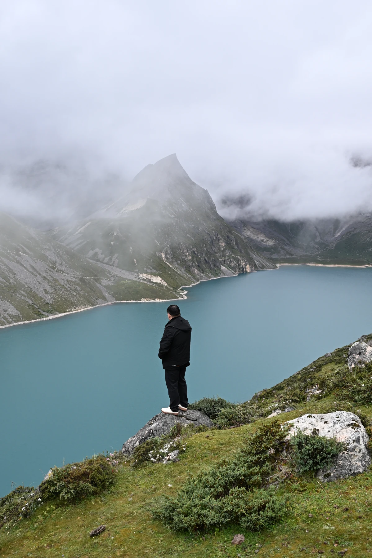 旅人站在碧色湖水与云山前