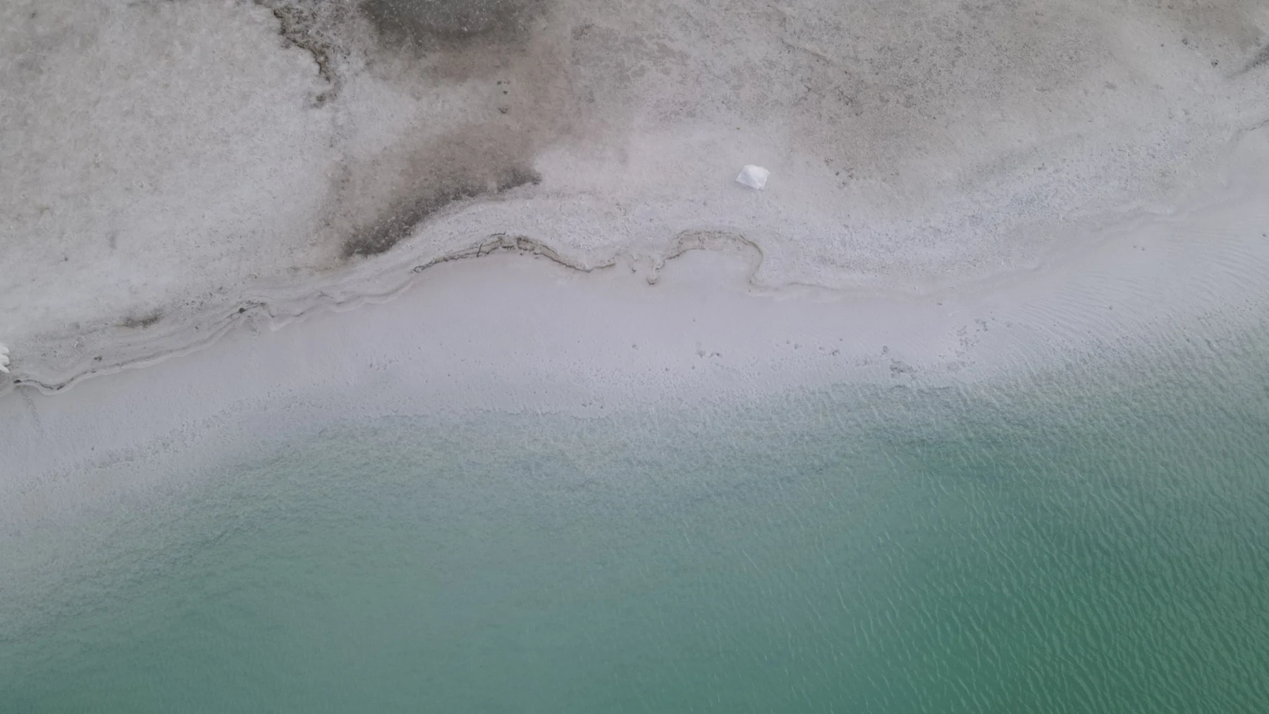 灰白雾气、浅绿色水面与湖岸的俯瞰画面